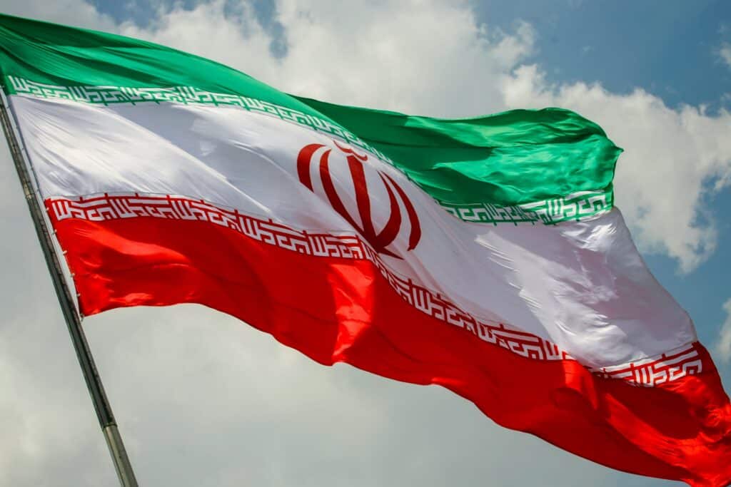 an iranian flag with blue sky behind