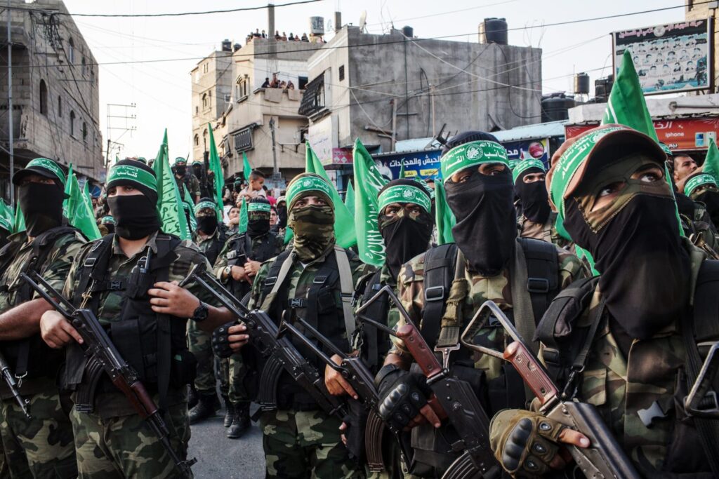 a group of hamas freedom fighters standing in gaza. They are holding guns and wearing masks