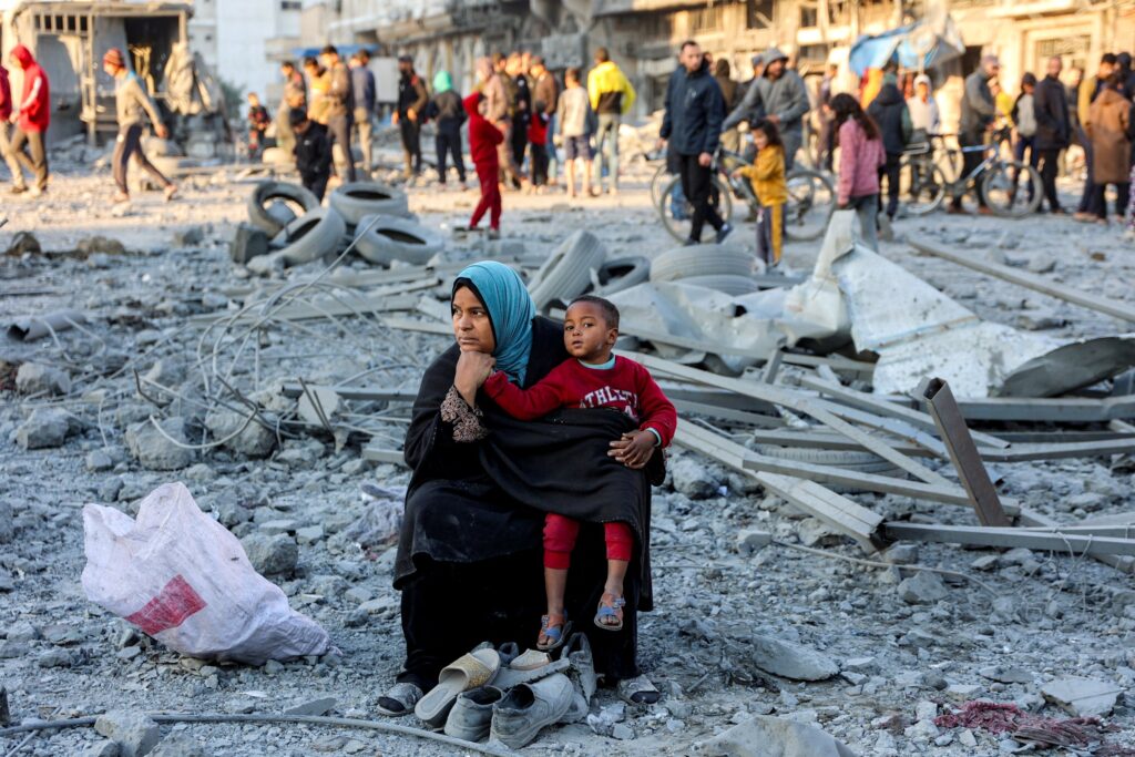 a Palestinian woman sitting while holding a small little boy with herself