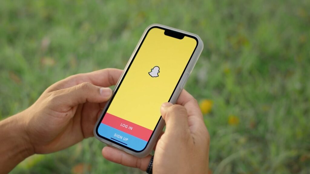 a hand holding a phone with snapchat app opened on the screen